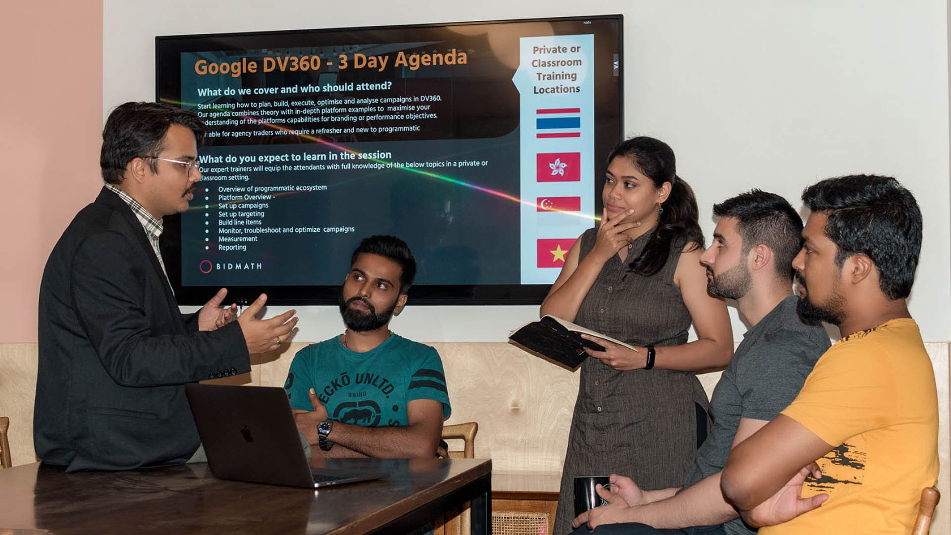 A trainer talking attendees through the DV360 agenda in front of a screen